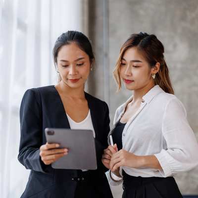 Two women discussing Kbank application on a tablet