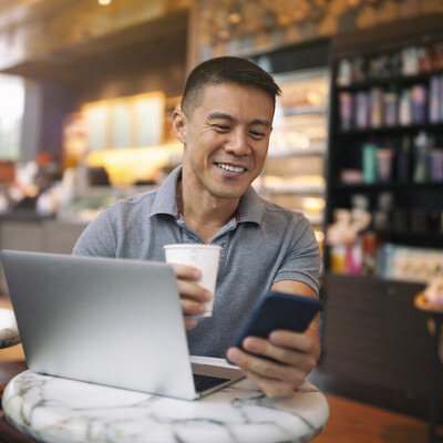 Man checking a mobile phone with laptop
