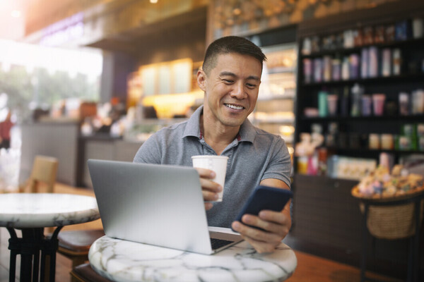 Man checking a mobile phone with laptop
