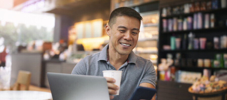Man checking a mobile phone with laptop