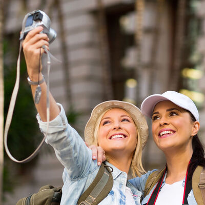 Two women travellers taking selfie before an old house
