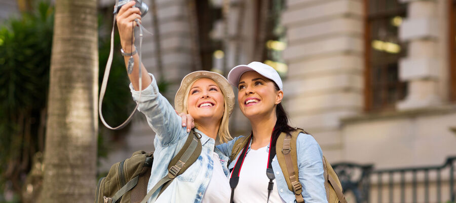 Two women travellers taking selfie before an old house