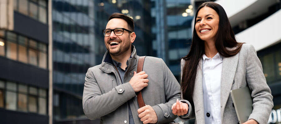 Male and female managers before a glass building